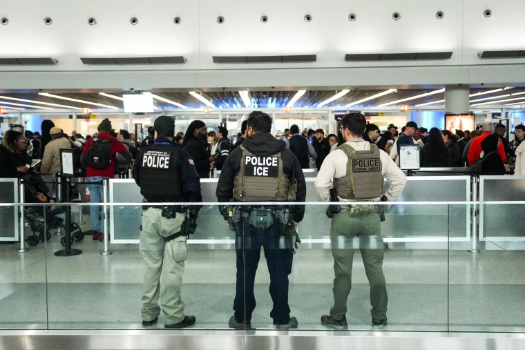Armed ICE and DHS agents standing at a crowded airport terminal