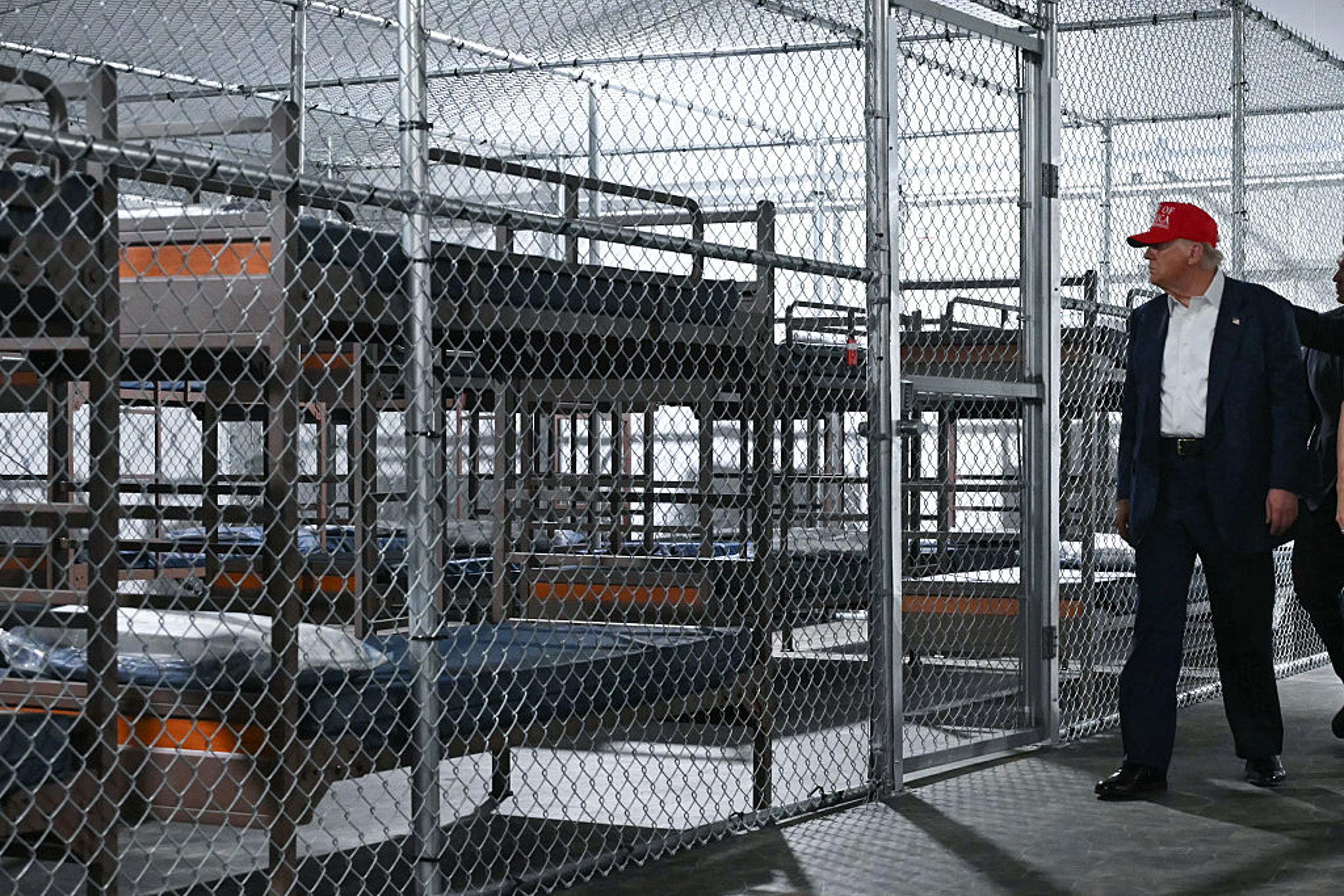 President Trump touring a chain-link immigration detention facility with rows of bunks