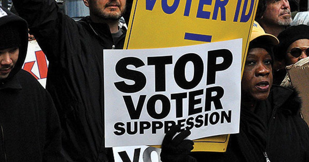 Demonstrators holding "Stop Voter Suppression" signs at a rally