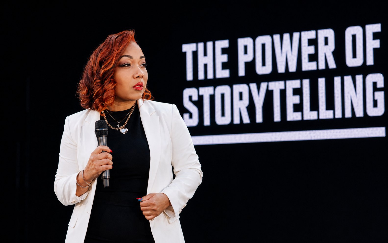 Hannah Naomi Jones speaking on stage in front of a The Power of Storytelling screen